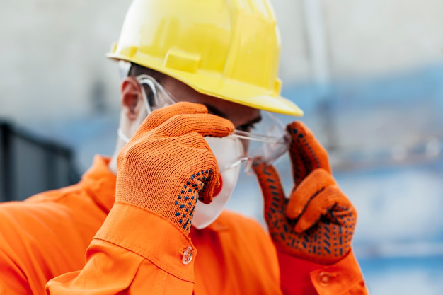 Construction worker wearing a full set of safety gear, including a hard hat, safety glasses, and a reflective vest.